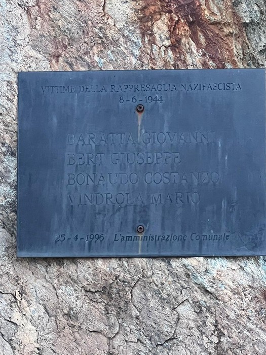 Targa in metallo scuro con iscrizione, fissata su una parete di roccia.