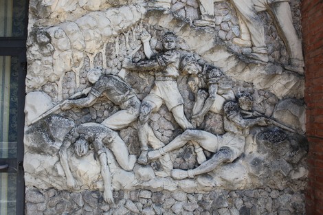 Bassorilievo che rappresenta figure umane in attività di lavoro, scolpito in una superficie rocciosa.