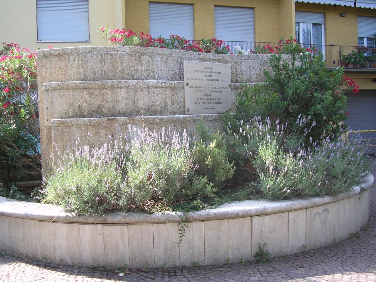 Monumento dedicato alla Liberazione, adornato da piante e fiori in un contesto urbano.