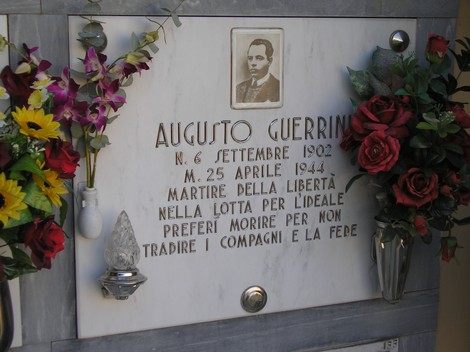 Sepolcro di Guerrini, un tributo al martire della libertà Augusto Guerrini, decorato con fiori commemorativi.