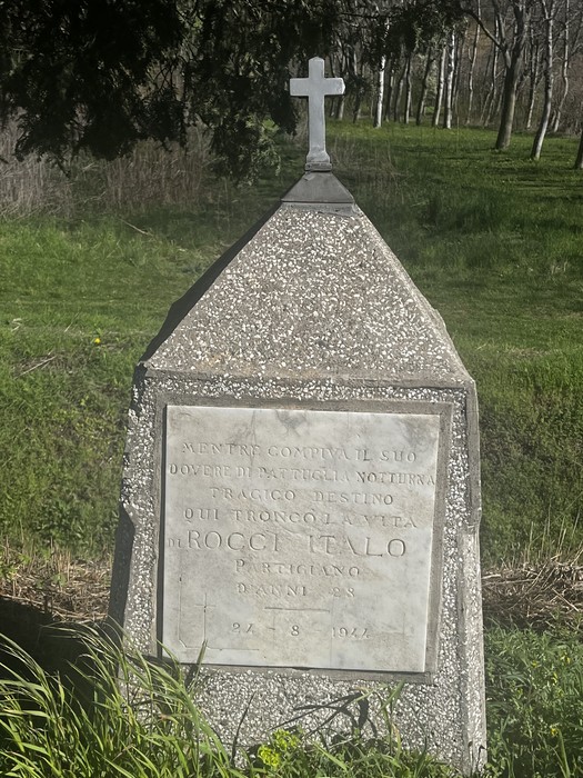 Cippo commemorativo a Rocci, dedicato a un evento storico, immerso nella natura circostante.