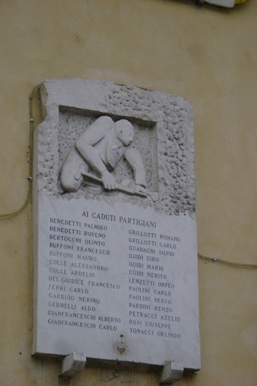 Lapide commemorativa dedicata ai caduti partigiani, con nomi incisi in memoria dei combattenti.