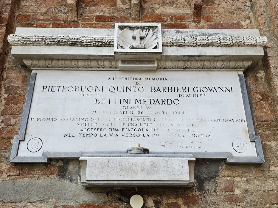 Lapide commemorativa dedicata a Pietrobuoni, Barbieri e Bettini, incisa su pietra, in un contesto storico.