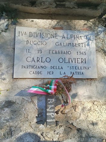 Lapide commemorativa in memoria di Carlo Olivieri, partigiano caduto per la patria, collocata su una roccia.