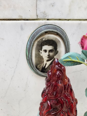 Un cippo commemorativo in memoria di una persona, con una foto in bianco e nero e un vaso di fiori.