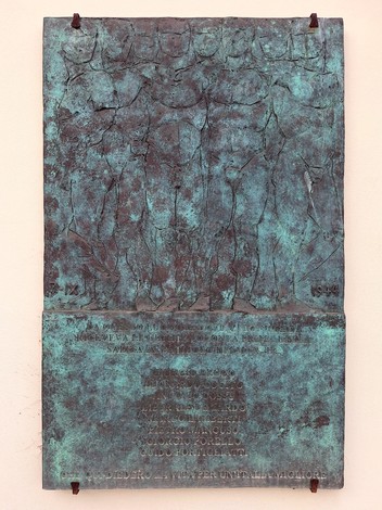 Targa in bronzo su parete, con figure in rilievo nella parte superiore e iscrizione nella parte inferiore.