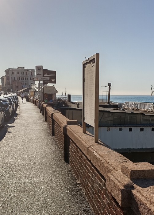 Lapide commemorativa dedicata ai caduti per la libertà, vista su un lungomare con il mare sullo sfondo.