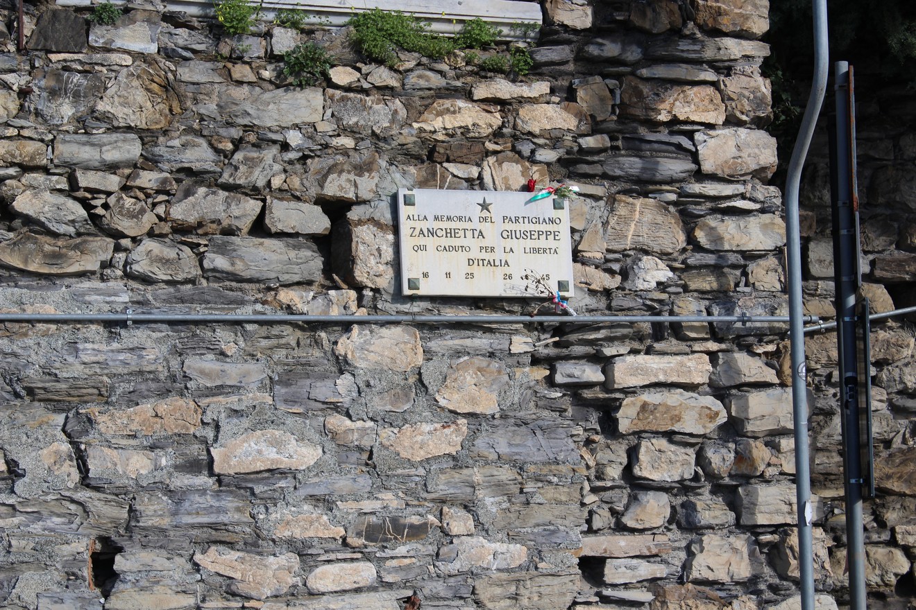 Lapide commemorativa di Giuseppe Zanchetta, affissa su una parete in pietra.
