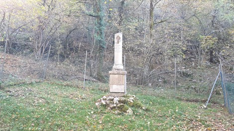 Monumento dedicato a Rossi, Nocente ed Olivieri, immerso nella natura, circondato da alberi e vegetazione.
