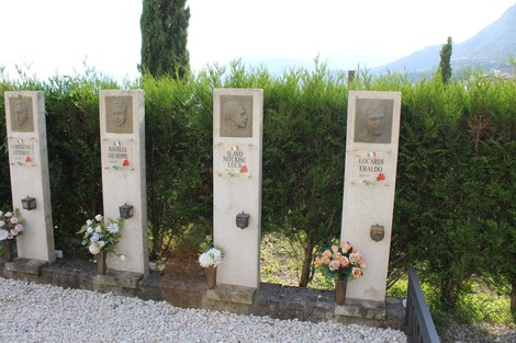 Il Sacrario dei Tredici Martiri, con stele commemorative e fiori, immerso in un paesaggio verde e panoramico.