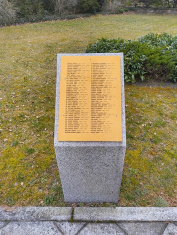 Targa commemorativa con i nomi dei caduti al Cimitero militare italiano di Zehlendorf, circondata da un prato verde.