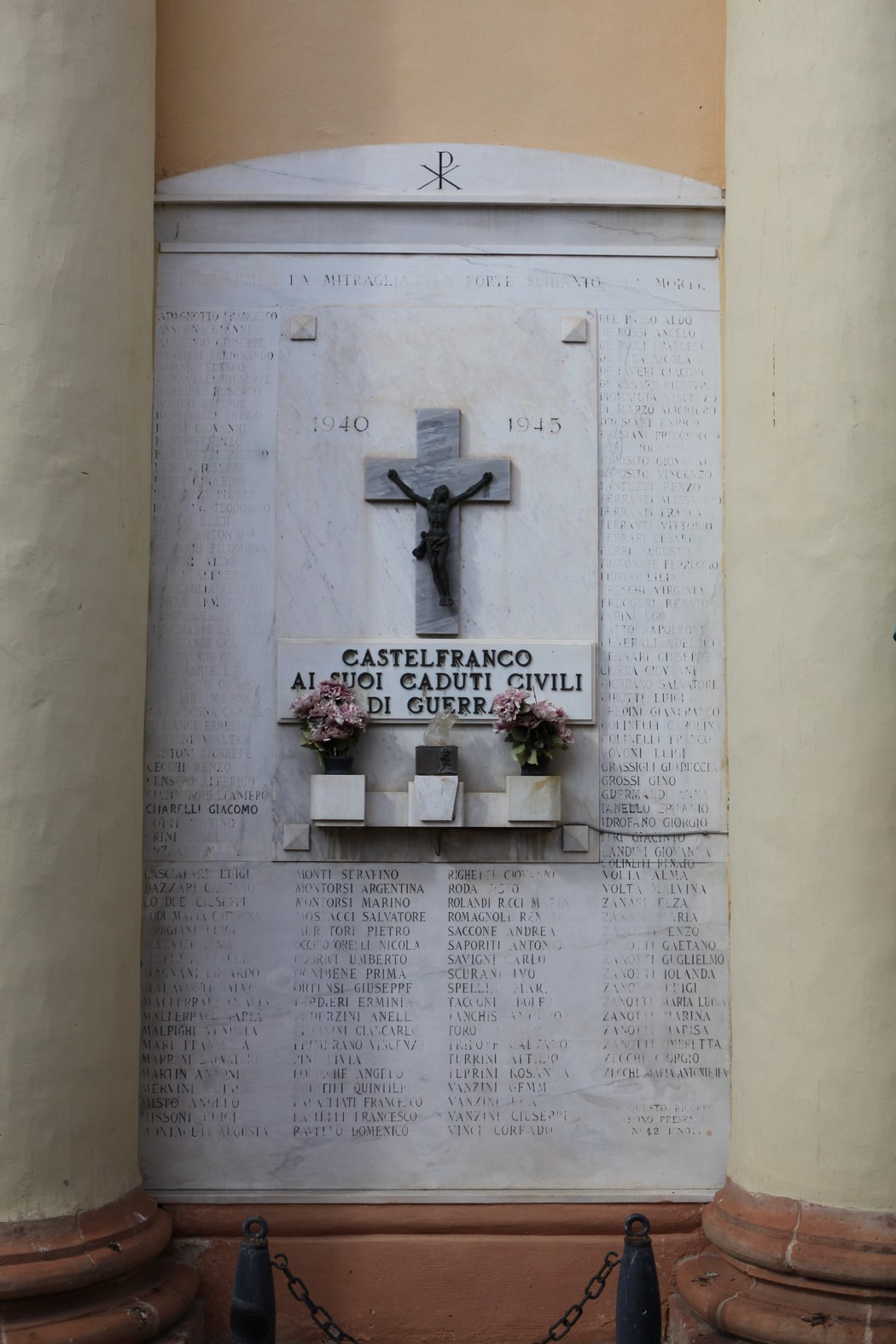Lapide commemorativa dedicata ai caduti civili, con croce e fiori, in un contesto di rispetto e memoria.