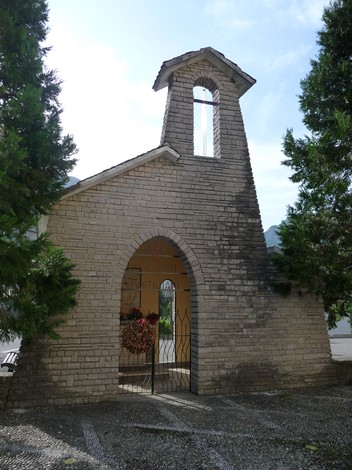 Cappella con tetto a spiovente, ingresso ad arco e decorazioni floreali, dedicata ai partigiani caduti.