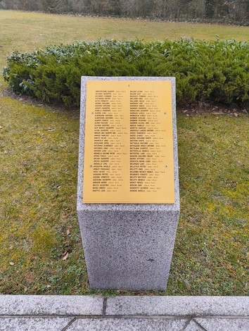 Targa commemorativa con nomi di caduti al Cimitero militare italiano di Zehlendorf, circondata da verde.