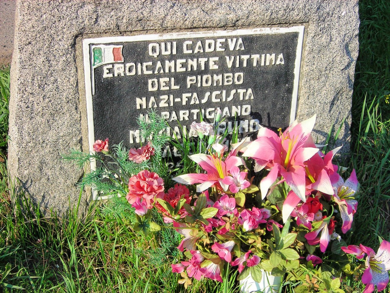Cippo commemorativo con fiori, in ricordo di un partigiano vittima del regime nazi-fascista.