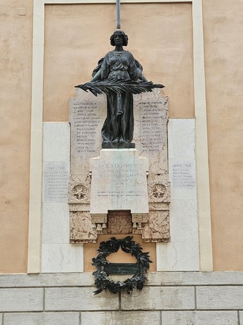 Lapide commemorativa con scultura che onora i caduti di Isola Dovarese, decorata con una corona di alloro.