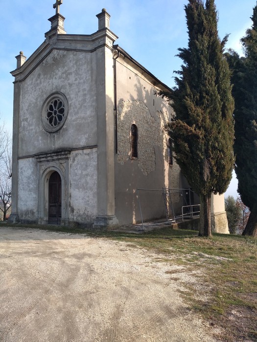 Fronte del Sacrario delle vittime dell'eccidio di Villa Martuzzi, con alberi e un cielo sereno.