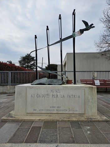 Monumento ai Caduti di Runzi, commemorazione con scultura stilizzata e iscrizioni dedicate ai caduti per la patria.