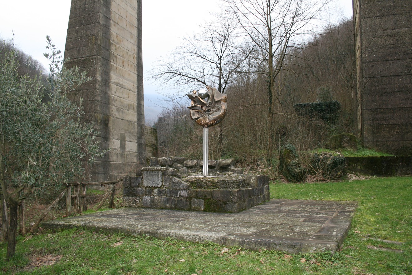 Monumento commemorativo ai bombardamenti della Porrettana, situato tra rovine e natura, simbolo di memoria e resilienza.