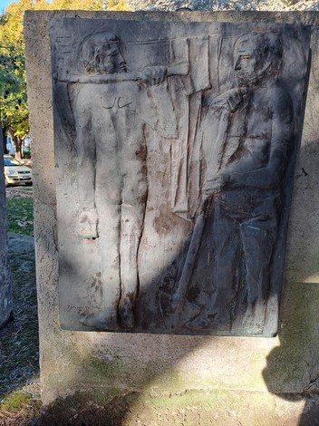 Rilievo bronzeo del Monumento ai Caduti, raffigurante figure umane in un contesto di commemorazione.