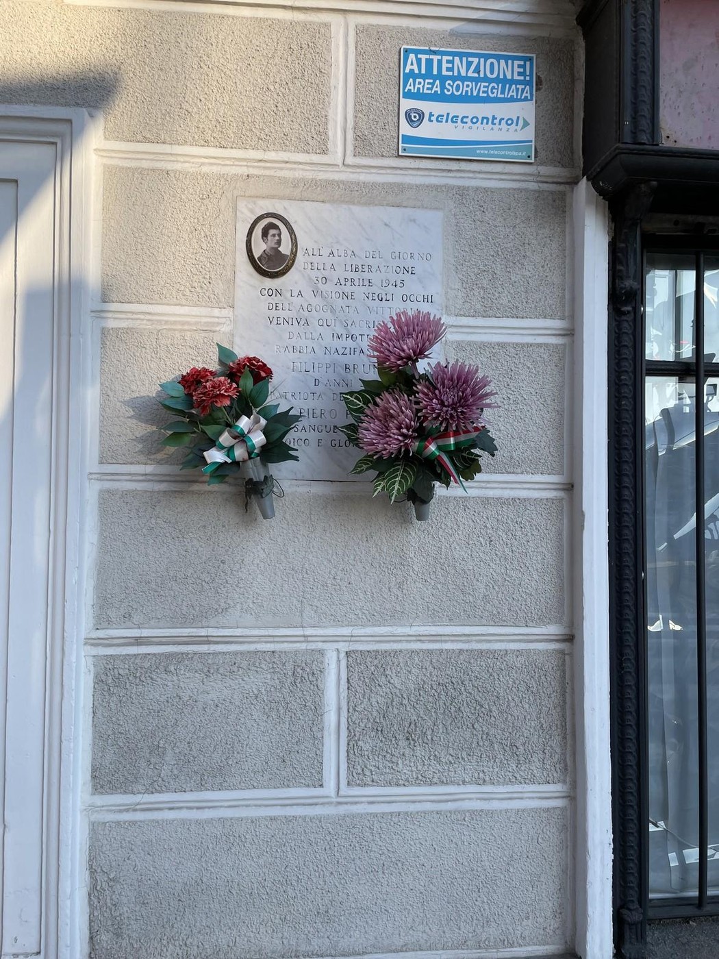 Lapide commemorativa a Filippi, adornata con fiori, in onore di un evento significativo.