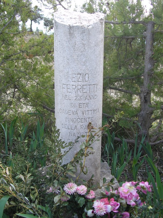 Cippo commemorativo dedicato a Ezio Ferretti, vittima innocente della violenza, immerso nella natura.