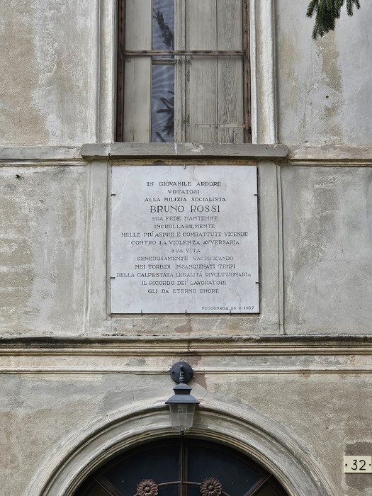 Lapide commemorativa dedicata a Bruno Fossi, affissa su una facciata di un edificio storico.