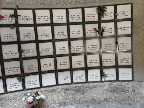 Monumento Ossario dedicato ai caduti partigiani, con targhe commemorative e fiori di ricordo.
