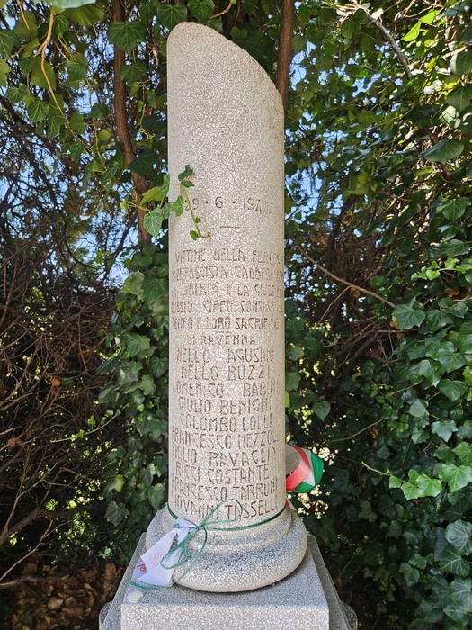 Cippo commemorativo dedicato ai Martiri dell'eccidio dell'Aeroporto di Forlì, con iscrizioni e decorazioni.