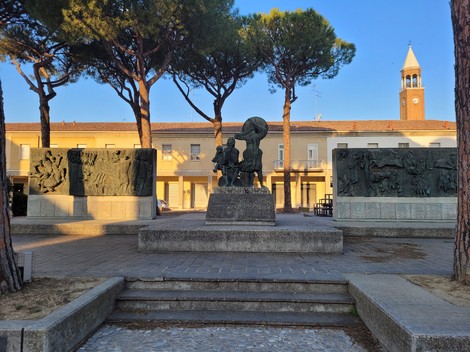 Monumento alla Resistenza, simbolo di libertà e memoria storica, circondato da alberi e un paesaggio urbano.