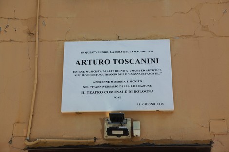 Lapide commemorativa dedicata ad Arturo Toscanini, situata a Bologna, con dettagli sulla sua vita e carriera.