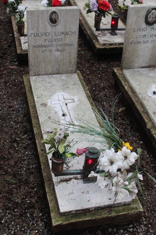 Tombe immerse in un’atmosfera di rispetto, con fiori e candele in memoria dei caduti per la Libertà.