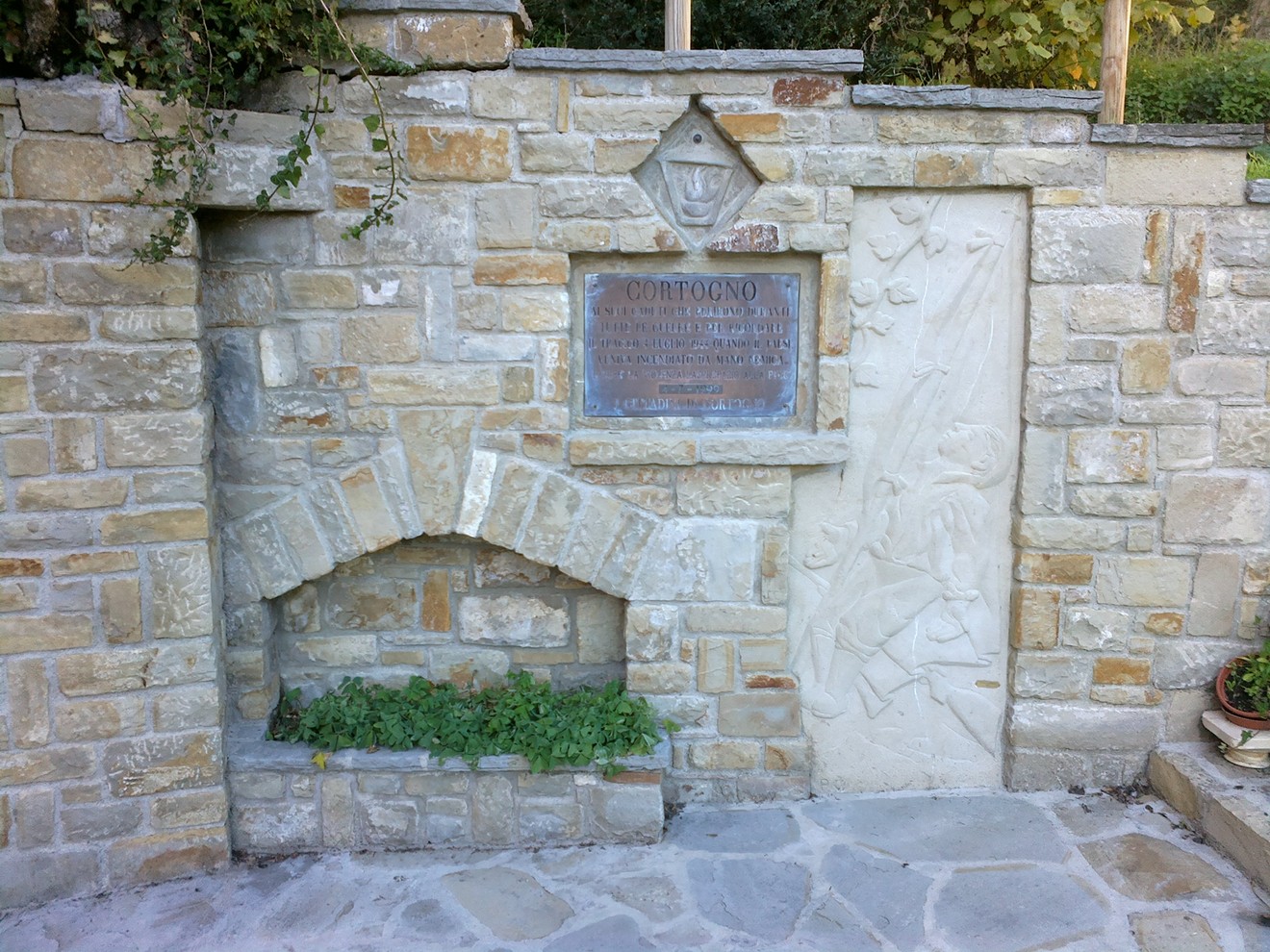 Monumento in pietra dedicato ai Caduti e al ricordo dell'incendio del paese, simbolo di memoria e resilienza.