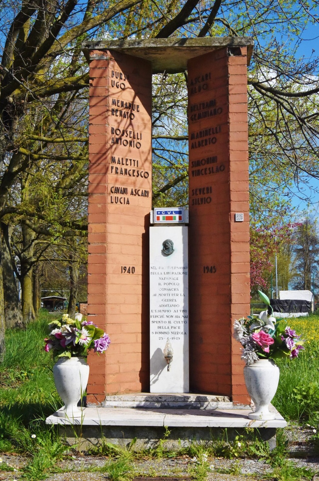 Monumento commemorativo dedicato a tutti i caduti, situato a San Donnino, con nomi incisi e decorazioni floreali.