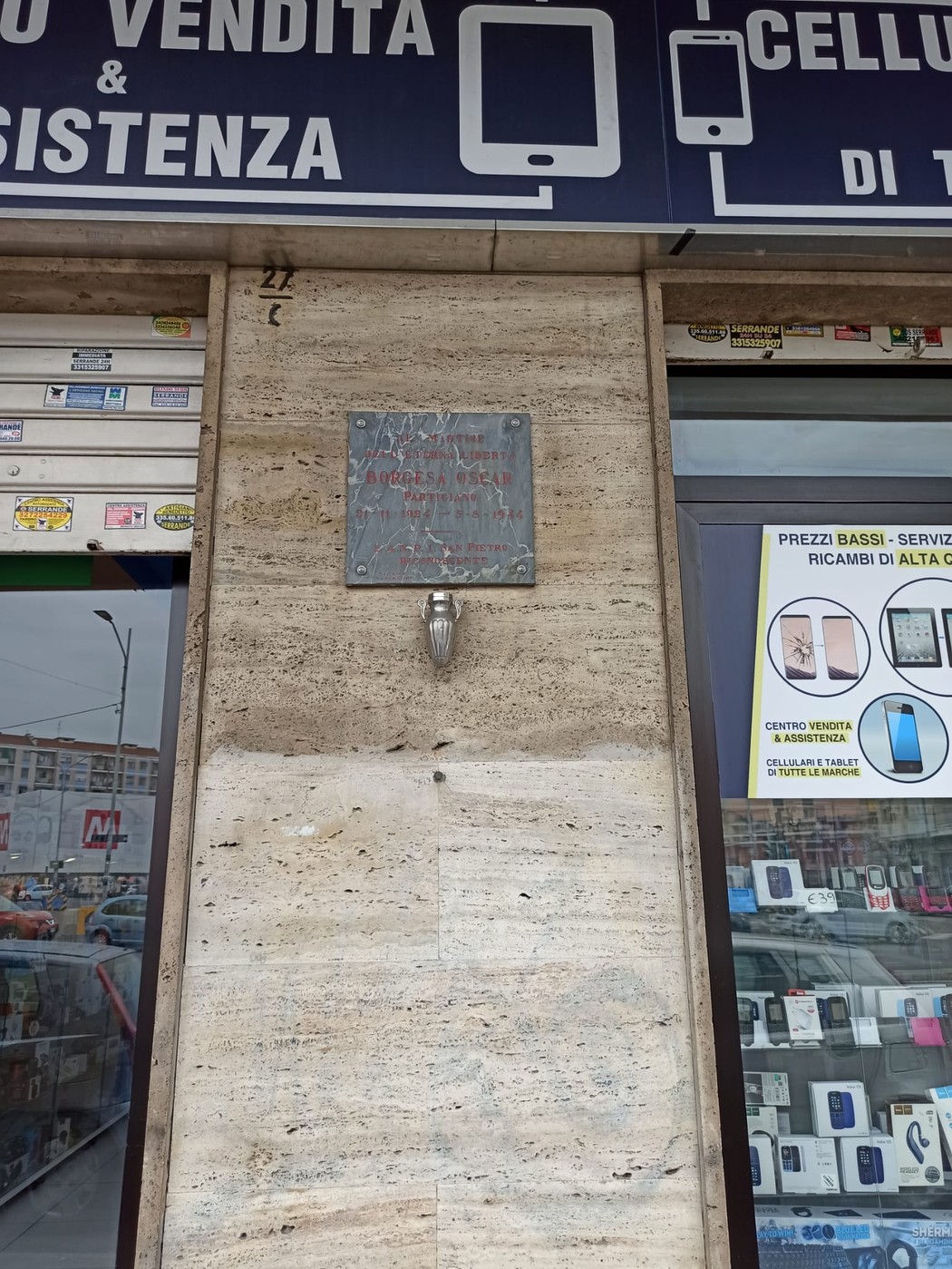 Lapide commemorativa situata all'esterno di un negozio di elettronica a Borgesa.