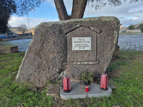 Monumento a Cocco, una pietra commemorativa con dedica in un'ambientazione verde e tranquilla.