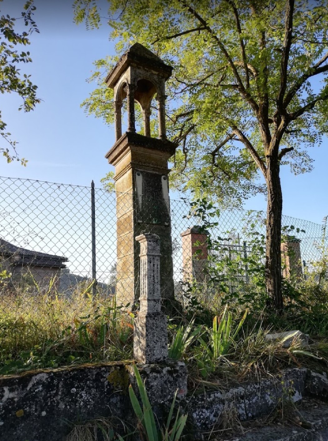 Cippo commemorativo circondato da vegetazione, situato in un'area rurale a Nugareto.