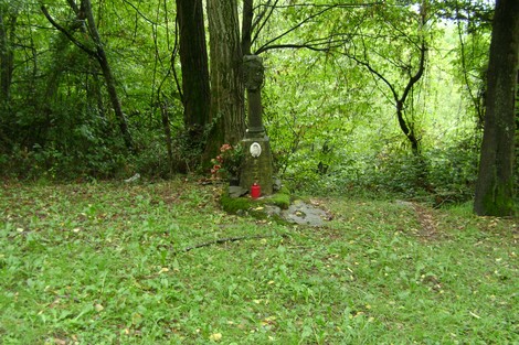 Cippo commemorativo circondato da verd foliage, immerso nella tranquillità della natura.