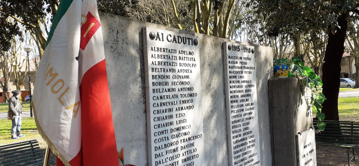 Monumento commemorativo ai caduti di Imola, con nomi e omaggi floreali.