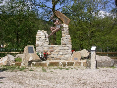 Monumento ai caduti di Botteghino di Zocca, una scultura in pietra con elementi commemorativi e decorazioni floreali.
