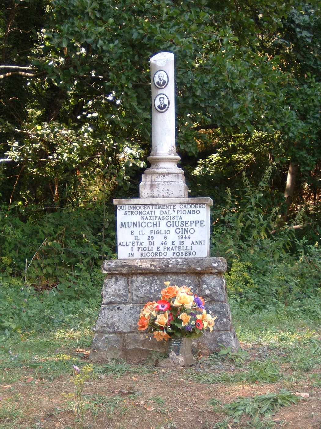 Cippo commemorativo dedicato a Giuseppe e Gino Municchi, con fiori e un ambiente naturale circostante.