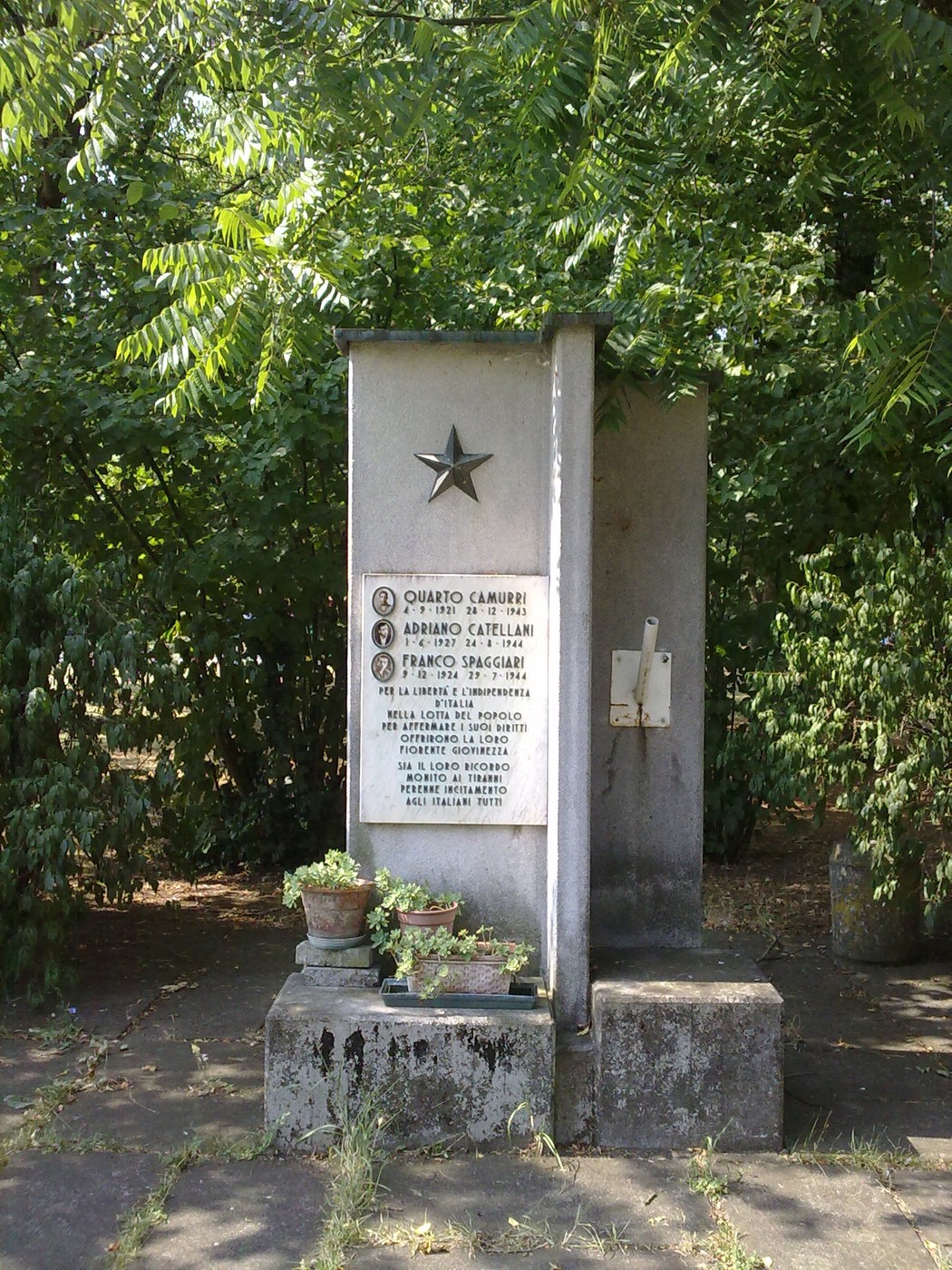 Monumento commemorativo a Camurri, Catellani e Spaggiari, immerso nel verde, con lapide e decorazioni.