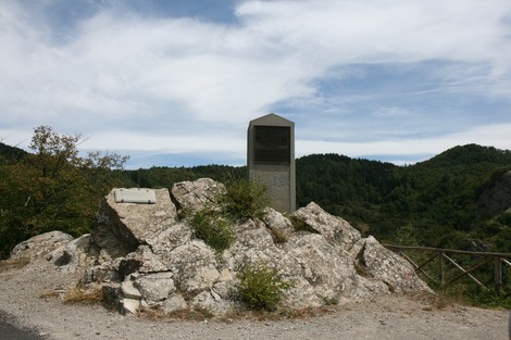 Cippo commemorativo della Battaglia del Monte Altuzzo, situato tra le colline, circondato da natura.