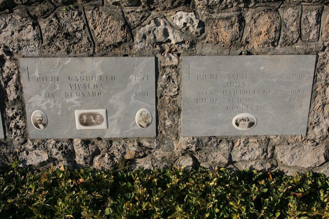 Ossario di Sant'Anna di Stazzema con lapidi commemorative e fotografie in un contesto di pietra.