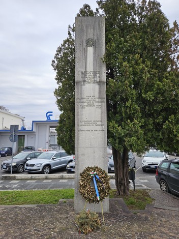 Monumento ai cantierini caduti nella guerra di Liberazione, con decorazioni floreali e alberi circostanti.