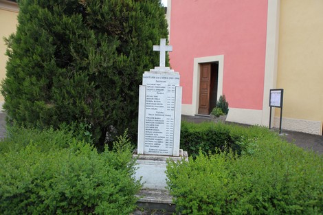 Monumento ai caduti di Croce del Biacco immerso nel verde, con una croce e un elenco di nomi incisi.