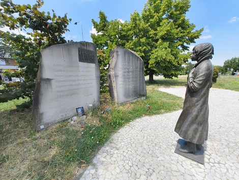 Monumento commemorativo con statue e iscrizioni per l'eccidio di Pratomaggiore, immerso nel verde.