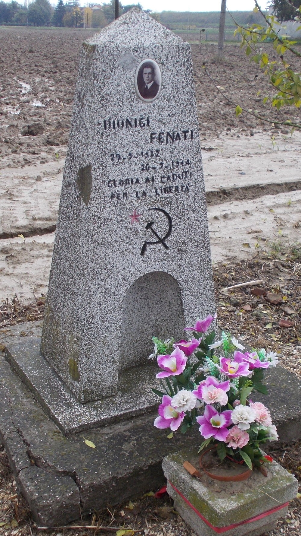 Cippo commemorativo di Fenati, onore ai caduti per la libertà, con fiori posati ai suoi piedi.