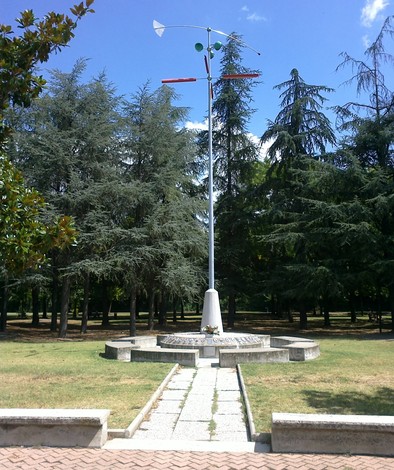 Monumento alla Pace e alla Libertà circondato da alberi, con una scultura moderna e un sentiero che conduce al centro.