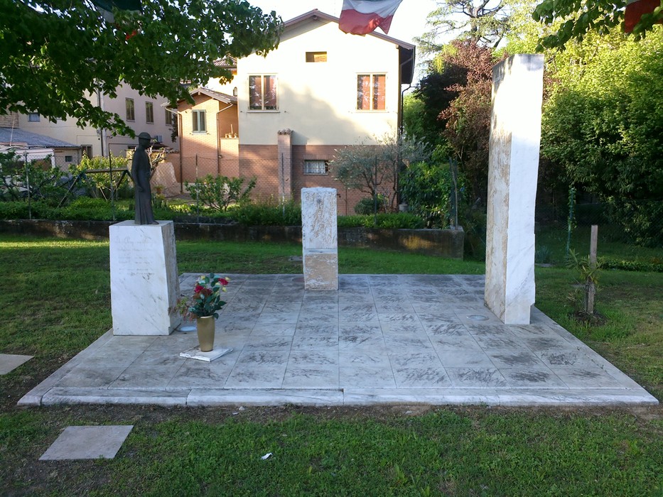 Monumento dedicato a Borghi, con colonne di marmo e statua, immerso in un verde giardino.
